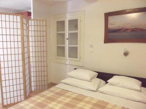 a bedroom with a bed with white pillows and a window at Studio In Einem Traditionellen Steinhaus, In Baska in Baška