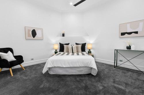une chambre blanche avec un lit et une chaise dans l'établissement Modern Tranquility in the heart of Tanunda, à Tanunda
