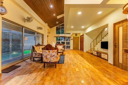 a living room with chairs and a tv and a pool at Gauri Villa by ELIVAAS 3-BHK Villa With Private Pool, Lounge, Garden & Bathtub With 360 Panoramic Hill Views Near Waterfalls in Kasāra
