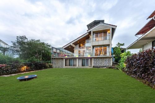 a house with a large lawn in front of it at Gauri Villa by ELIVAAS 3-BHK Villa With Private Pool, Lounge, Garden & Bathtub With 360 Panoramic Hill Views Near Waterfalls in Kasāra