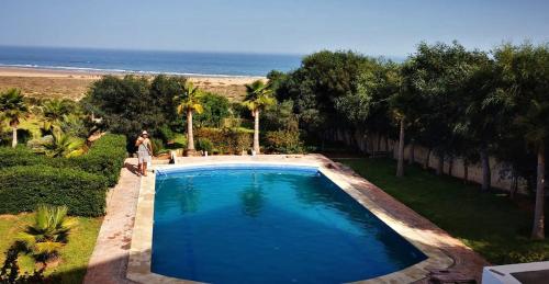 Aït Raïs AomarDar Skalli Essaouira - Oase am Atlantik的站在海滩旁游泳池旁的人