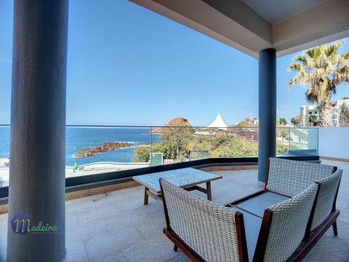 a balcony with two chairs and a table and the ocean at Pearls Beach Villa in Porto Moniz