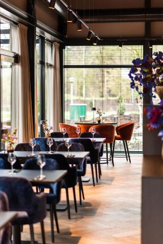 a restaurant with tables and chairs and large windows at Kampeerdorp de Zandstuve - Kindvriendelijke Vakantiepark in Rheeze