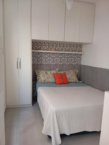 a bedroom with a bed with white cabinets and red pillows at Beira-mar in Santos