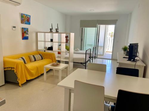a living room with a yellow couch and a table at Geysotur Torrox Playa Apartamentos in Torrox