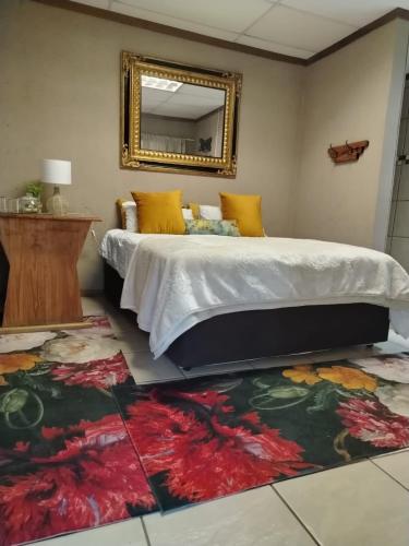 - une chambre avec un lit, un miroir et un tapis dans l'établissement Droombos Guestrooms, à Kuruman