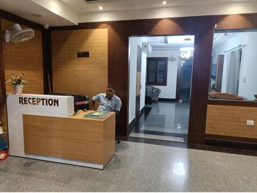 Hotal Glory Ganga في حاريدوار: رجل يجلس في مكتب الاستقبال في مكتب