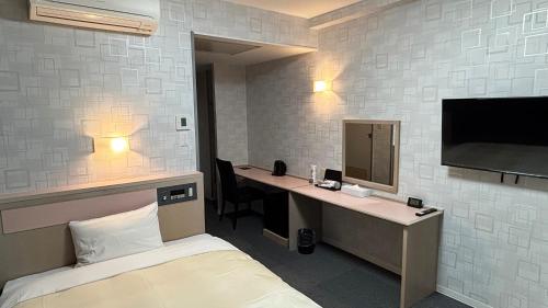 a room with a bed and a desk and a tv at ホテルテラス小名浜 in Iwaki