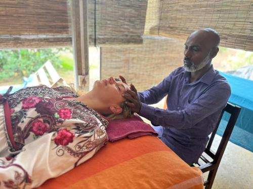 Ein Mann schneidet einer Frau die Haare in der Unterkunft Sirilaka Wedagedara in Alutwala