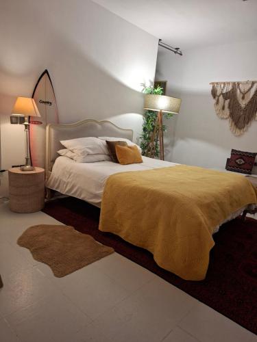 a bedroom with a bed with a yellow blanket and two lamps at Caruma Surf Hostel in Matosinhos