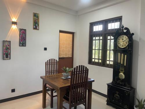 a dining room with a table and a grandfather clock at Woori House in Kamburugamuwa