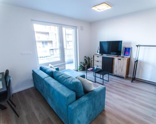 een woonkamer met een blauwe bank en een televisie bij Doctor's Cosy Apartment in Lamač