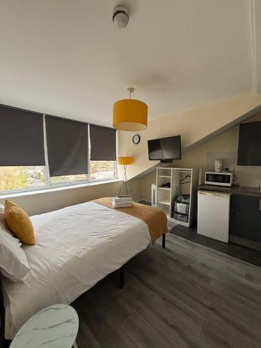a bedroom with a large bed and a kitchen at TLK Apartments & Hotel - Beckenham Junction in London