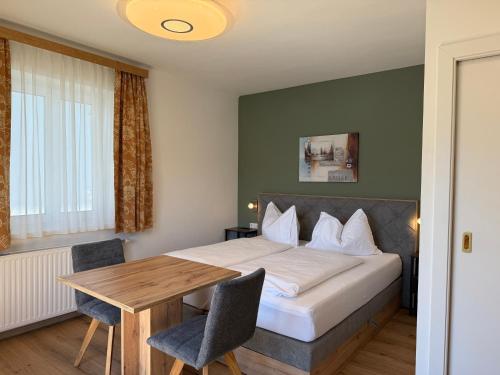 a bedroom with a bed and a wooden table at Hotel Seerose Wolfgangsee in St. Wolfgang