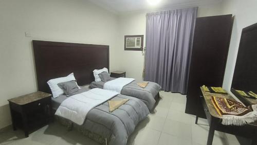 ein Hotelzimmer mit zwei Betten und einem Tisch in der Unterkunft نجم الحضارة للشقق المخدومة in Al-Hasa