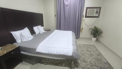 ein Schlafzimmer mit einem großen Bett mit weißen Laken und Kissen in der Unterkunft نجم الحضارة للشقق المخدومة in Al-Hasa