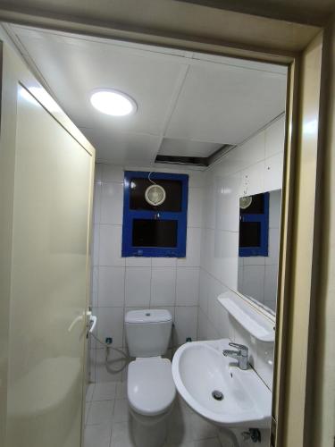 a white bathroom with a toilet and a sink at Rooms for family near to bus station in Ajman