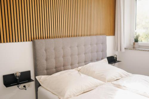 - une chambre avec un lit blanc et une grande tête de lit dans l'établissement Schöne Designer-Wohnung im Mangfalltal, à Bruckmühl