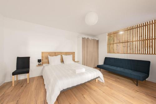 ein Schlafzimmer mit einem Bett und einer blauen Couch in der Unterkunft Le Loft du Castel Bas - Pause au cœur du Tarn in Castelnau-de-Montmiral