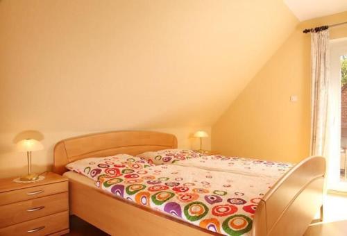 ein Schlafzimmer mit einem Bett mit geblümter Decke in der Unterkunft Komfortable Ferienwohnung in Bockhorn mit Großem Balkon - b48718 in Walsrode