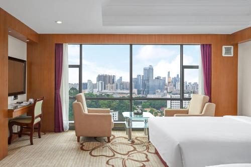 ein Hotelzimmer mit einem Bett und einem großen Fenster in der Unterkunft Nanyang King's Gate Hotel--Free Shuttle Service to Canton Fair in Guangzhou