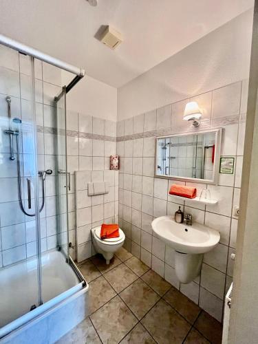 a bathroom with a sink and a toilet and a shower at Pension Villa HarzFokus - Frühstück inklusive in Wernigerode