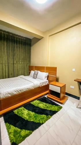 ein Schlafzimmer mit einem Bett und einem grünen Teppich in der Unterkunft Wyne's Hotel in Mbale
