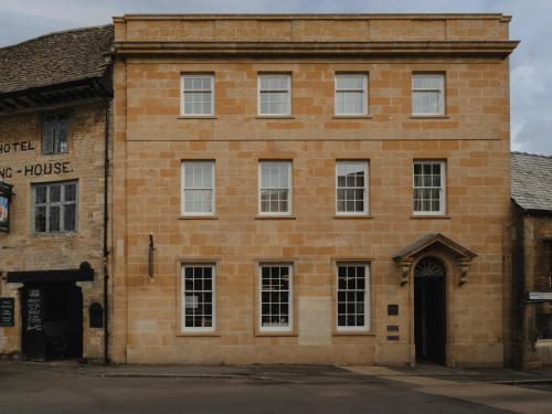 ein altes rotes Backsteingebäude mit einer Tür in der Unterkunft Luxury Apartment with Roof Terrace - Cotswolds in Stow on the Wold