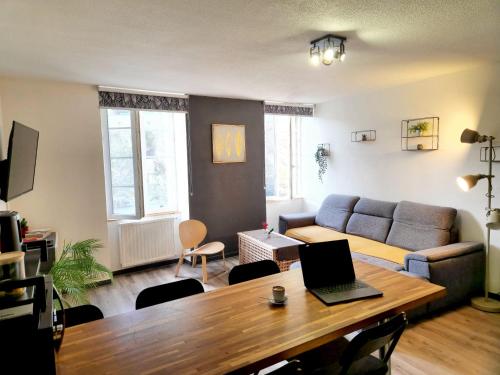 ein Wohnzimmer mit einem Sofa und einem Tisch mit einem Laptop in der Unterkunft Le DrômArdèchois - Gîte meublé Ardèche - WIFI Parking - Écolodgîte Drôme ardèche in Tournon-sur-Rhône