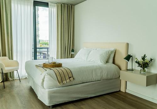 a white bedroom with a bed and a balcony at RentUp Suites Palmas Park Buenavista in Victoria