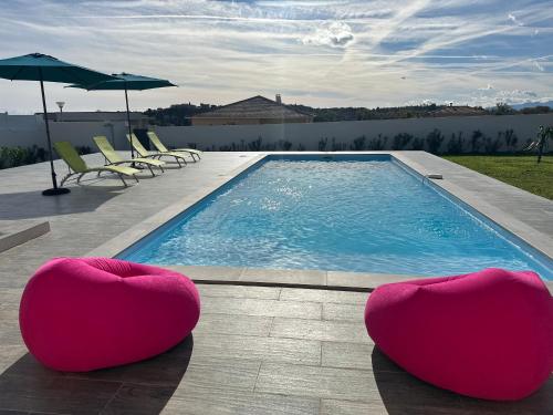 a swimming pool with two pink chairs and a swimming pool at Spacieuse villa standing de 220m2 in Aléria