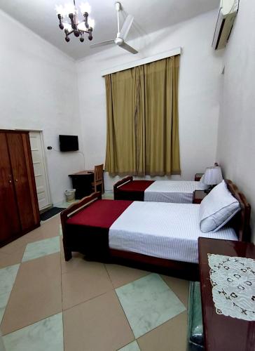 a hotel room with two beds and a television at City House Guesthouse in Cairo