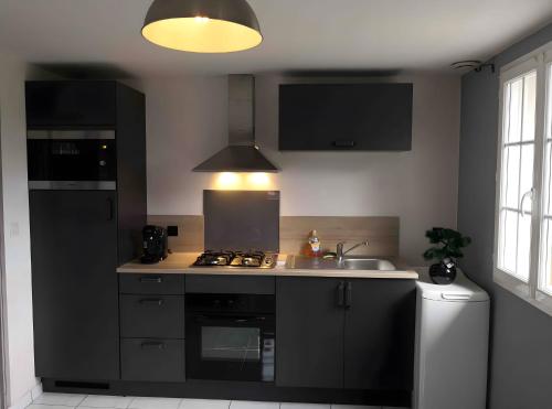 - une cuisine avec des placards noirs et un évier dans l'établissement Gîte de Rosemont, à Saint-Pol-sur-Ternoise