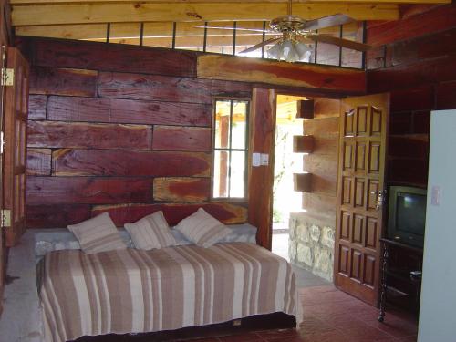 a bedroom with a bed and a wooden wall at Cabañas Ojos del Viento in Villa Giardino