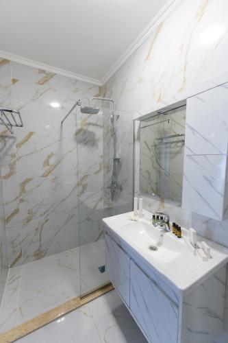 a white bathroom with a sink and a shower at Chuxuryurd Hotel in Shamakhi