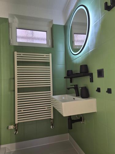 Un baño verde con lavabo y espejo. en Appartment Zweierlei, en Zingst