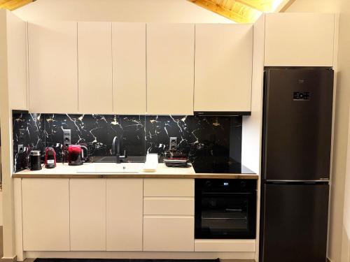 eine Küche mit weißen Schränken und einem schwarzen Kühlschrank in der Unterkunft Villa Sokratis Mountain View in Porti 