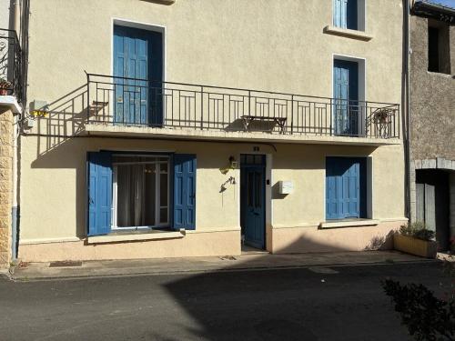 a building with blue doors and a balcony at Spacious Village House in Ginoles with Garden in Ginoles