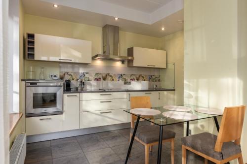 a kitchen with white cabinets and a table and chairs at Elite centre, free parking, ultra-desirable 1 of 1, lux view in Rīga