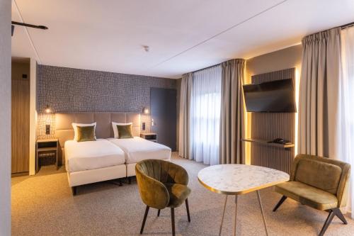 a hotel room with a bed and a table and a chair at Hotel Asteria in Venray