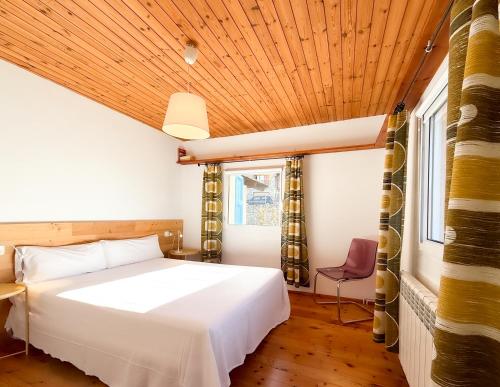 ein Schlafzimmer mit einem weißen Bett und einer Holzdecke in der Unterkunft Blue House in Urtx