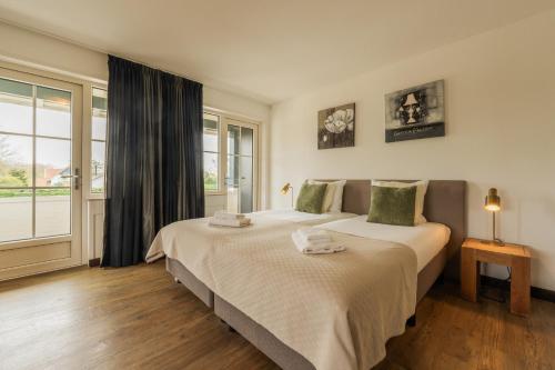 a bedroom with two beds and a window at Strandhotel Dennenbos in Oostkapelle