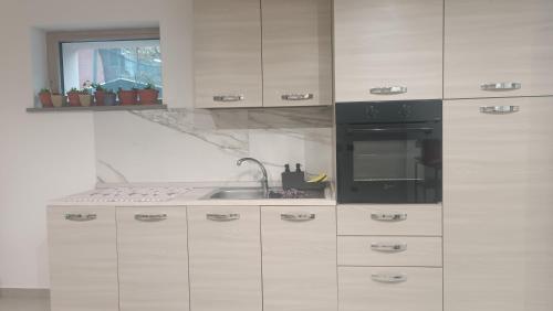 eine Küche mit weißen Schränken und einem schwarzen Gerät in der Unterkunft Casa del gelso in Canale