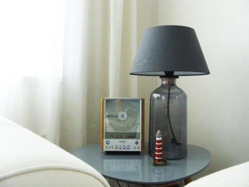 霍勒姆的住宿－Chalet Zilt Ameland，玻璃桌上的一盏灯和一个钟,床上