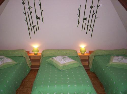 a bedroom with two green beds and two lamps at L Eucalyptus in Aumeville-Lestre
