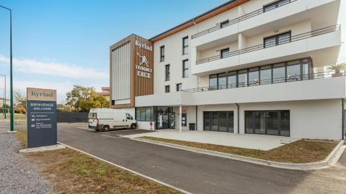a building with a van parked in front of it at KYRIAD DAX - Saint Paul lès Dax in Saint-Paul-lès-Dax