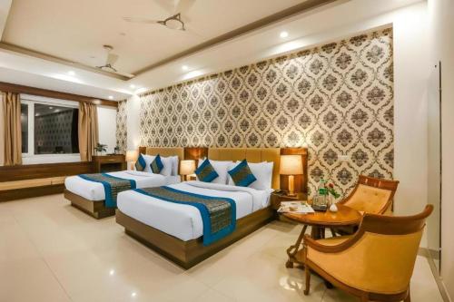 a hotel room with two beds and a table and a desk at Hotel Almati Inn Near Delhi Airport - With Free Airport Pickup in New Delhi