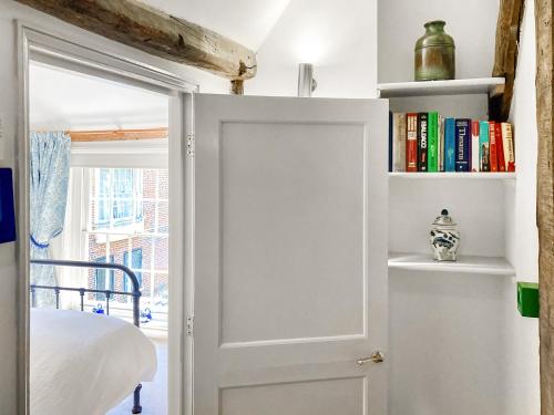 a door leading to a bedroom with a bed and books at The Friars Apartment, Eastbridge Hospital in Canterbury
