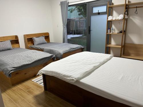 1 dormitorio con 2 camas y puerta a un patio en Home Dốc Mơ, en Xã Gia Tân