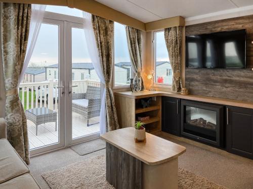 ein Wohnzimmer mit Kamin und Fernseher in der Unterkunft Maple 8 in Gristhorpe